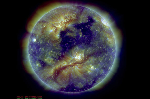 Debido a su temperatura del orden del millón de grados, la atmósfera solar emite ondas electromagnéticas en el rango Ultravioleta (UV) y X. Esta colorida imagen de la atmósfera solar, tomada por el instrumento Atmospheric Imaging Assembly (AIA) a bordo de la nave espacial Solar Dynamics Observartory (SDO), es una superposición de exposiciones en tres filtros Extremo-UV sensibles al rango 1 a 2 millones de grados. Las zonas más brillantes de esta imagen revelan el plasma más caliente atrapado en intensos, pero invisibles, campos magnéticos cerrados. Las zonas oscuras, que contienen plasma más frío, se denominan "agujeros coronales" y son regiones con campo magnético abierto. Estos "agujeros" son la fuente del "viento solar" que eventualmente impacta en la Tierra. Imagen cortesía del equipo del instrumento espacial AIA/SDO.